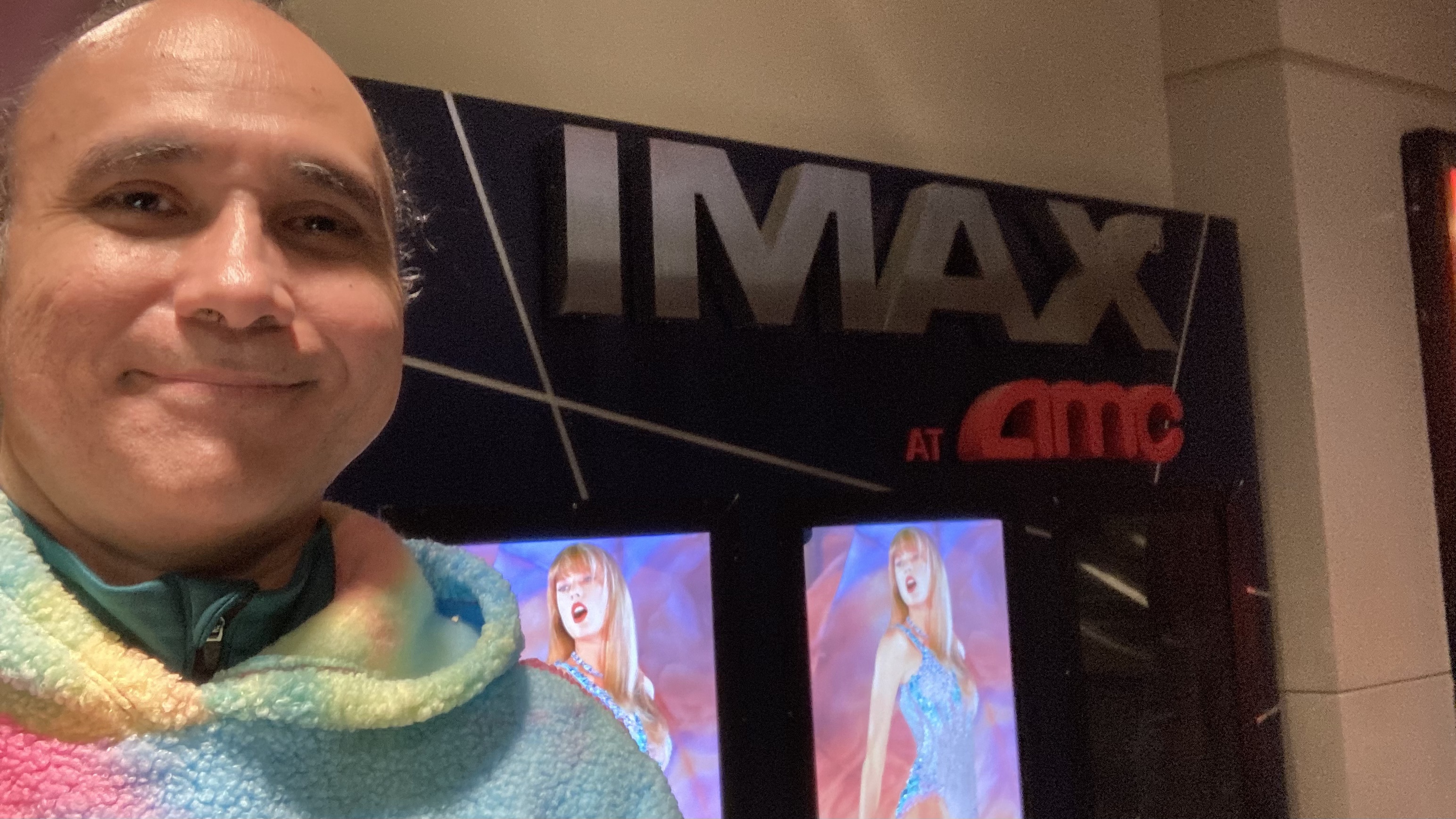 A photos of smile at AMC Lincoln Square in front of posters for Taylor Swift The Eras Tour Film in IMAX